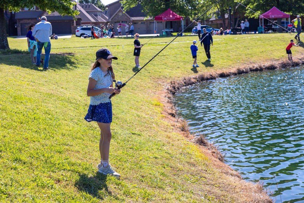 Little girl fishing on the banks of a pond