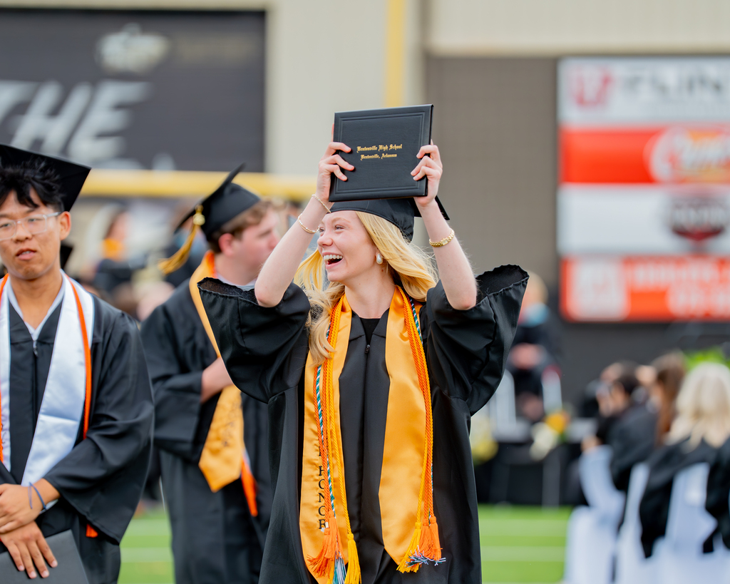 Bentonville High Senior Holding Up Her Diploma and Smiling