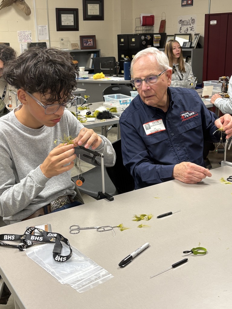 Fly fisherman teaching high school student how to create a fly