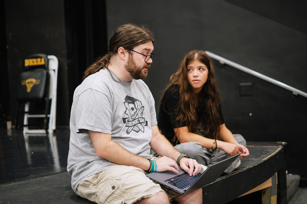 Picture of a teacher helping a student register for their upcoming classes on a laptop.