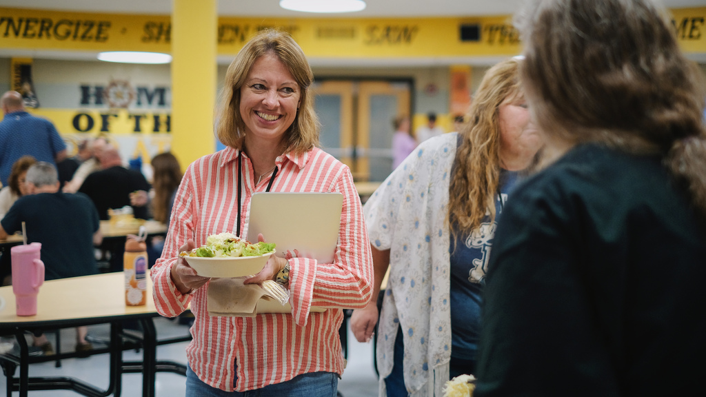 Principal being served lunch by community partners in school cafeteria.