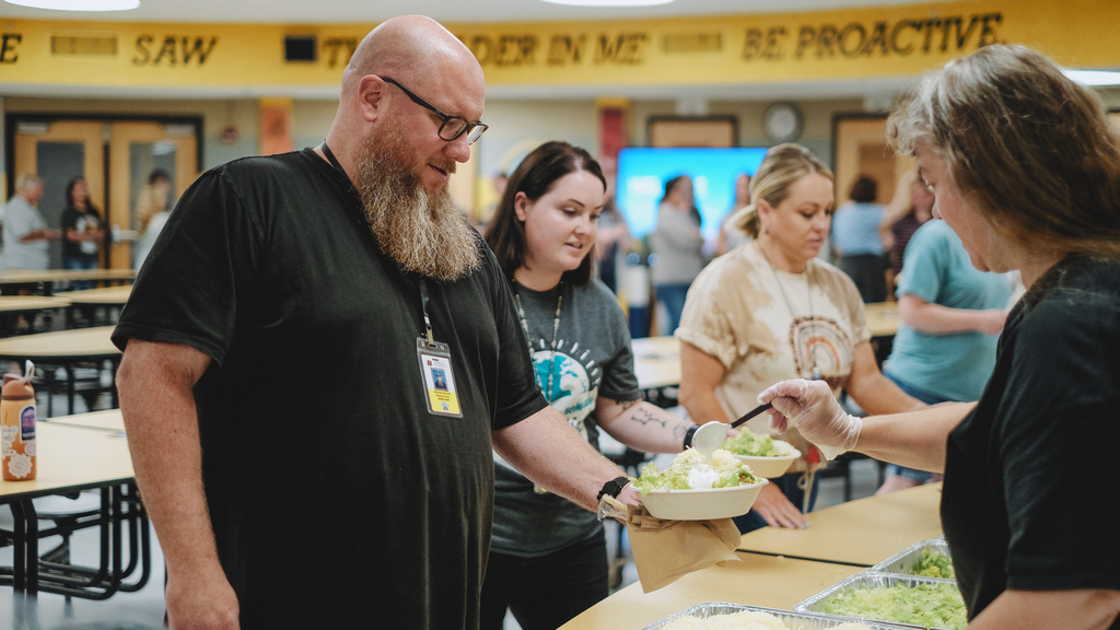 Band director being served lunch in cafeteria by community partners.
