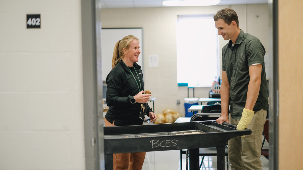 Superintendent delivering a cart of cookies to a teacher in her room.
