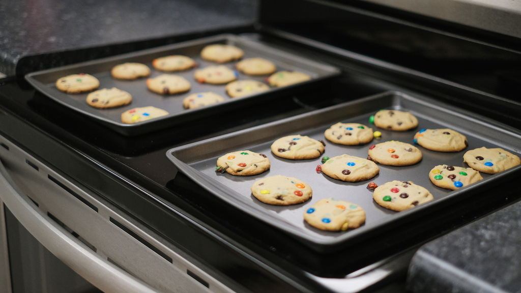 Two trays of Cookies sat on a stovetop.