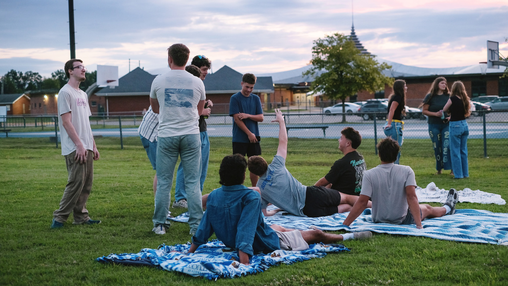 Seniors hanging out on the football field, watching the sun set behind their school.