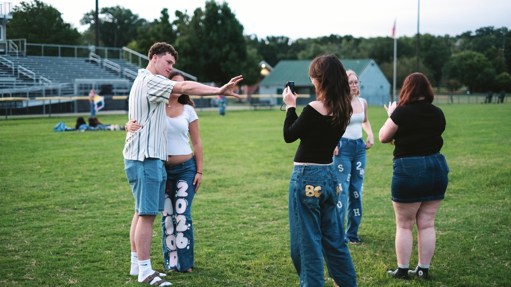 Seniors taking photos of each other on football field.