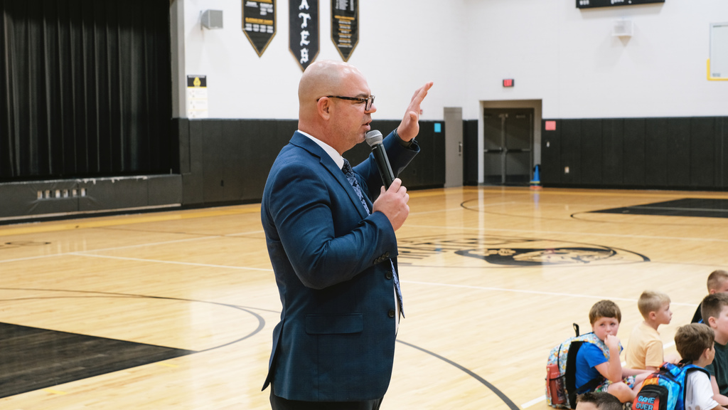 Elementary principal speaks to students in school gym.
