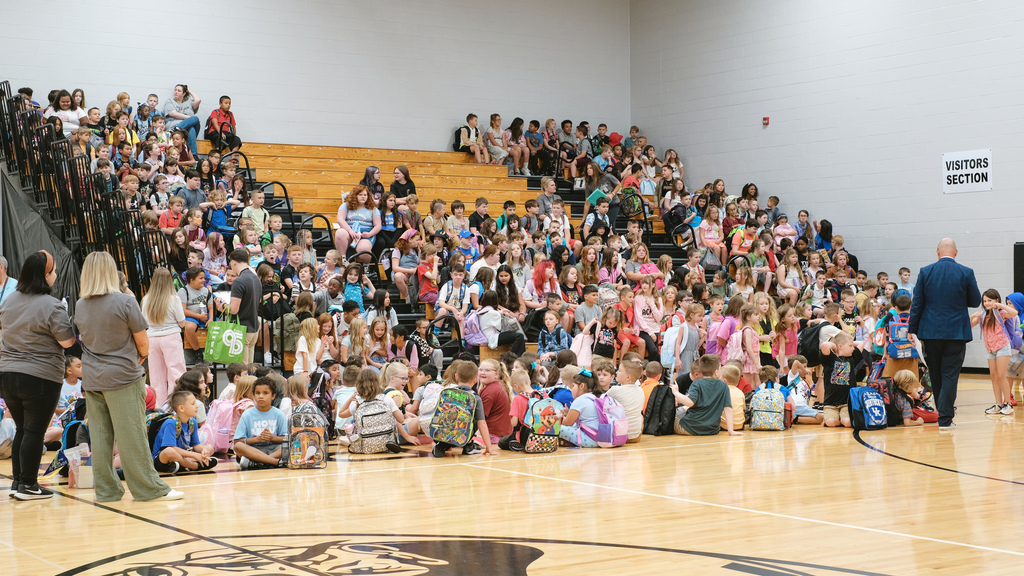 Bleachers filled with elementary school students in school gymnasium.