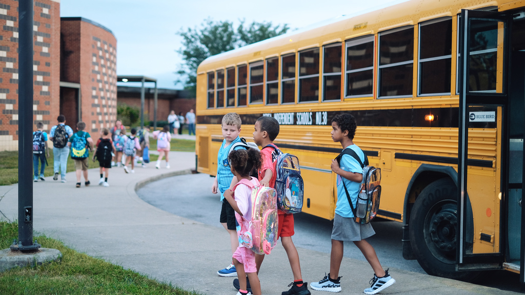 Elementary school students getting off their bus and heading into school.