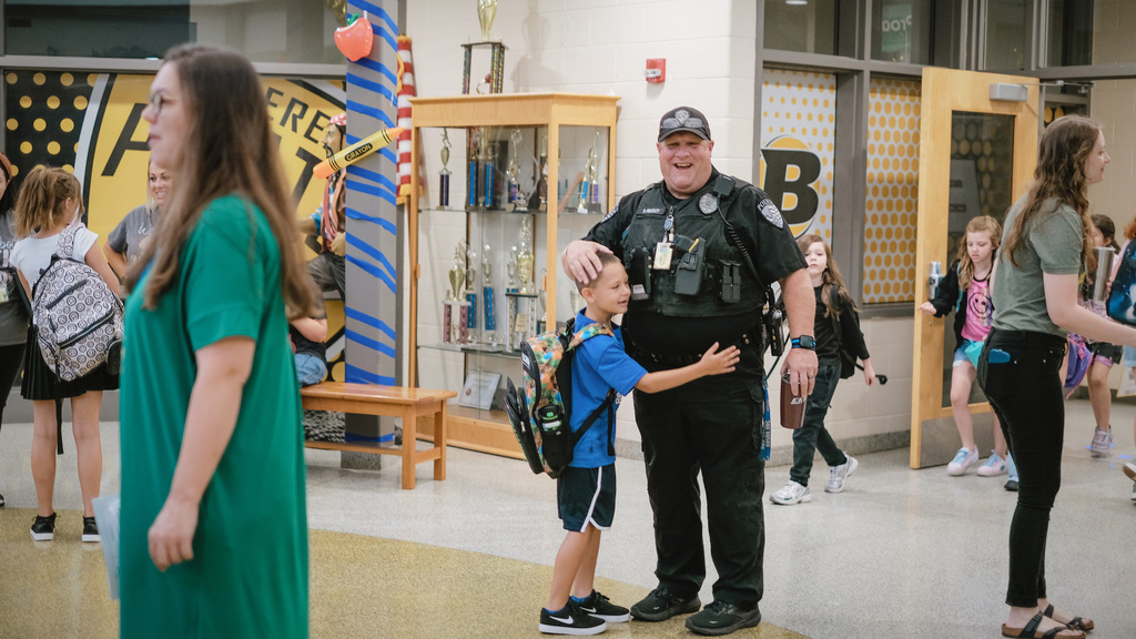 Student hugs School Resource Officer Bradley on his way into school.