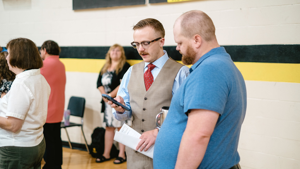 One teacher shows something to another teacher on phone.