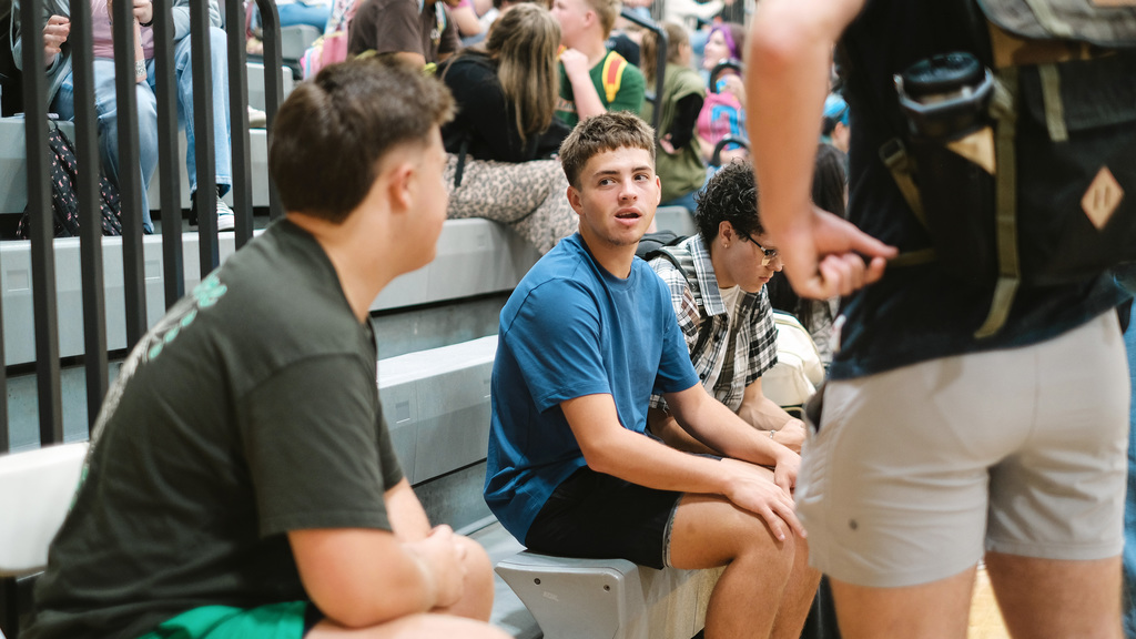 Students talk to each other on gym bleachers.
