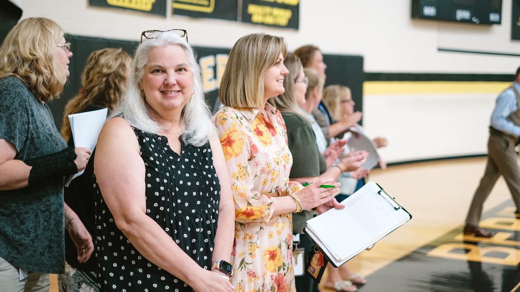 Teachers stand together in school gym.