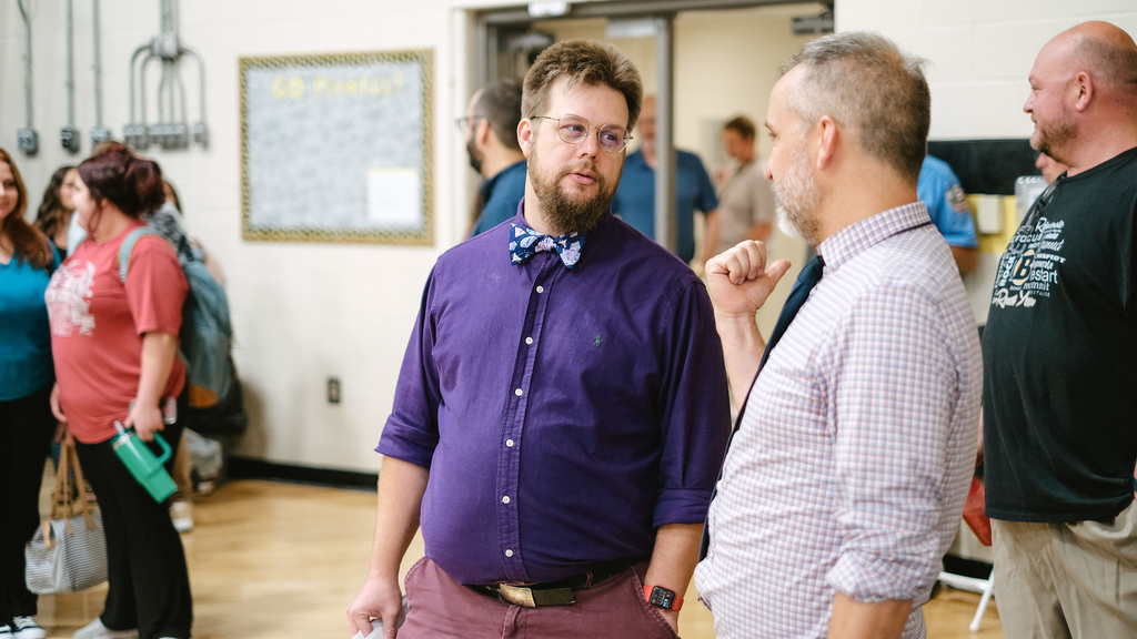 Teachers talk to each other in school gym.