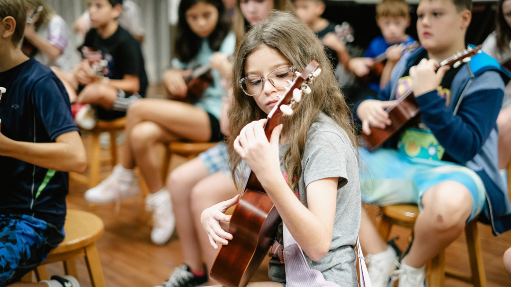 Elementary student plays ukulele in music class