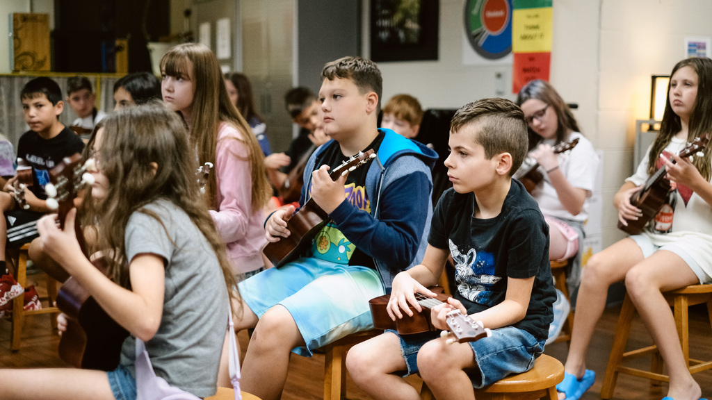 Elementary students play ukuleles in music class