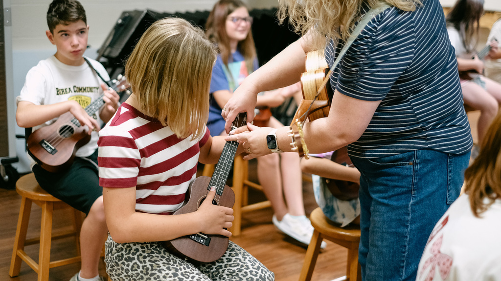 Music teacher shows students ukulele technique