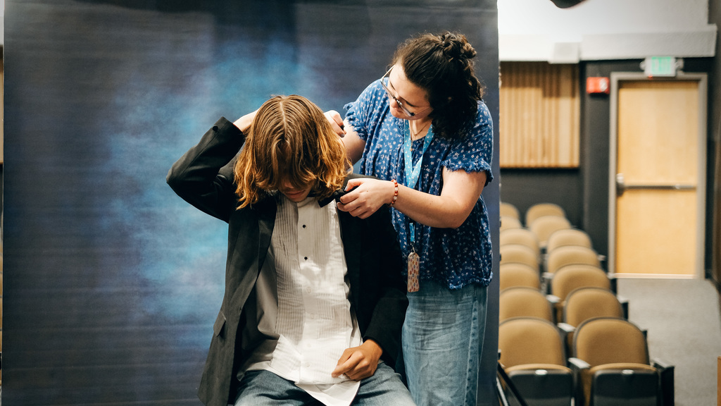 Photographer helping senior get dressed for his senior portrait