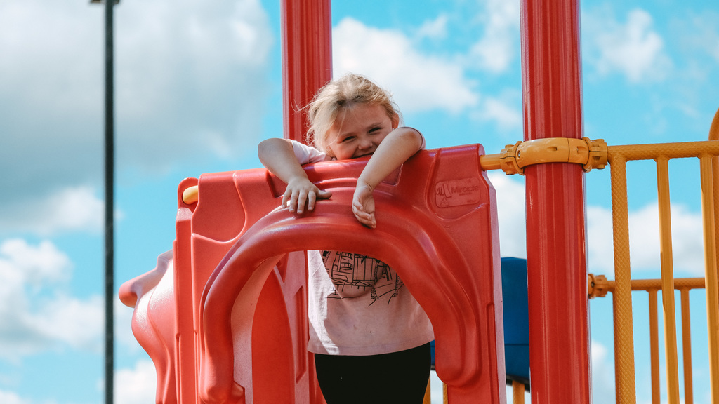 Elementary student standing at the top of a slide on the playground