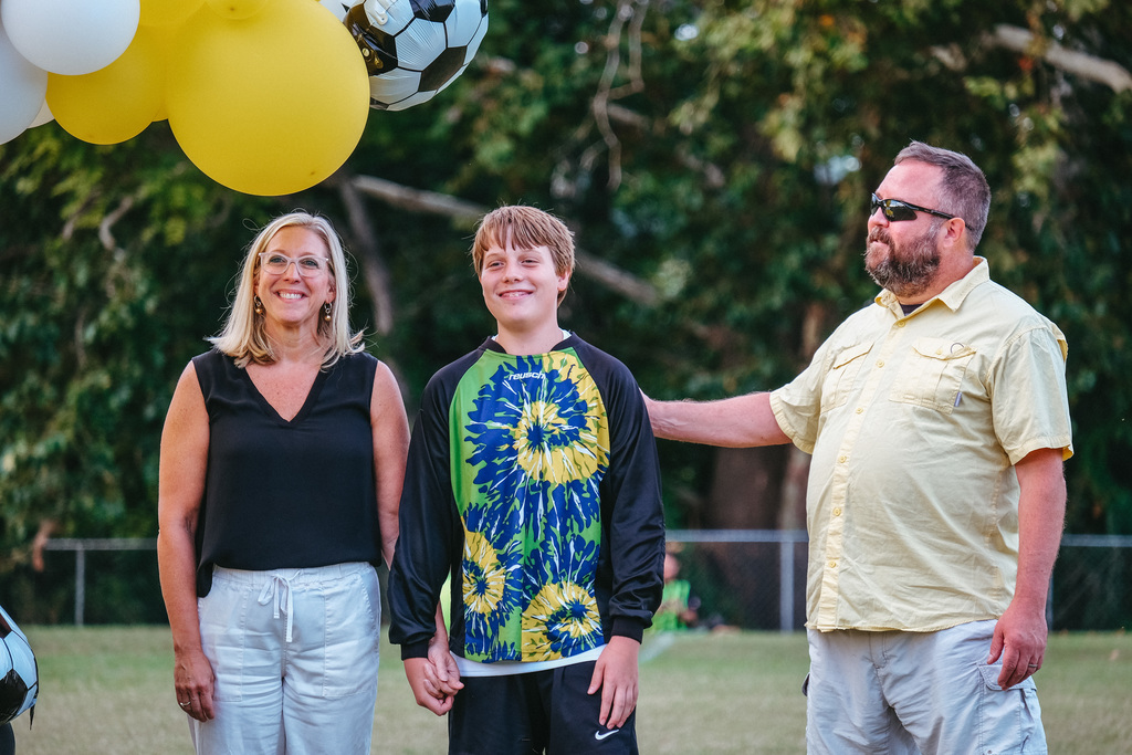 8th grader poses for photo with parents