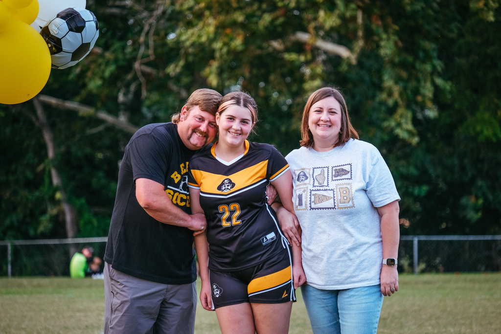 8th grader poses for photo with parents
