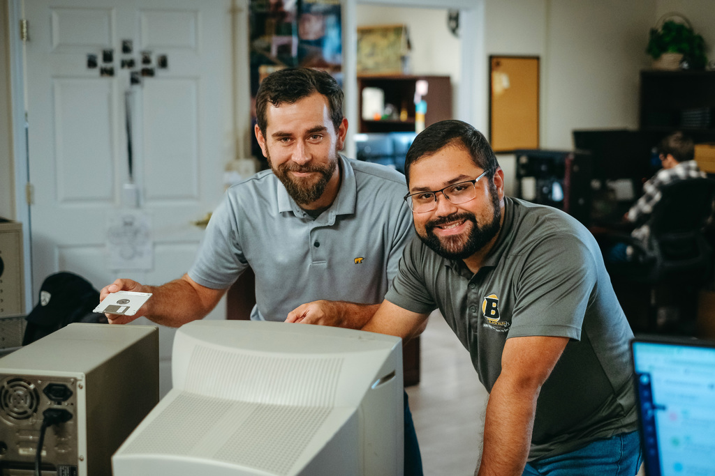 Technology staff posing with an ancient machine