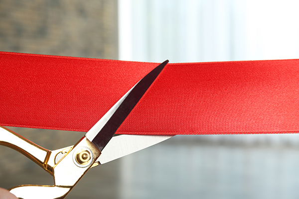 pair of scissors cutting a red ribbon