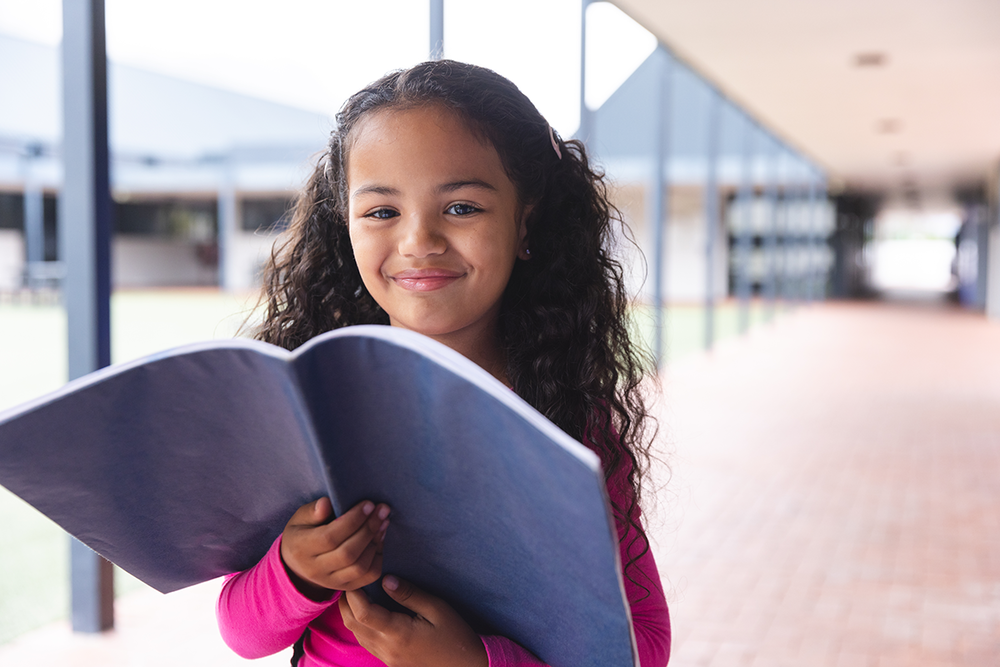 child smiling and holding a book