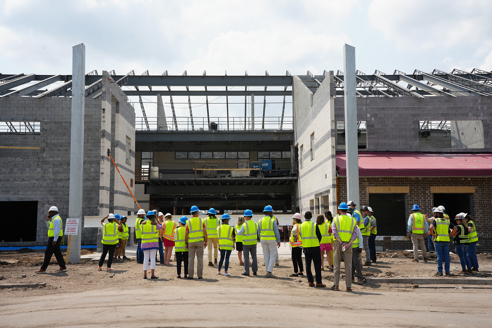 district officials in construction gear at standing with their backs to the camera and looking at Midtown Middle under construction
