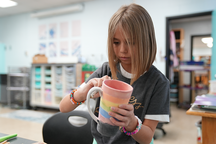 student painting mug