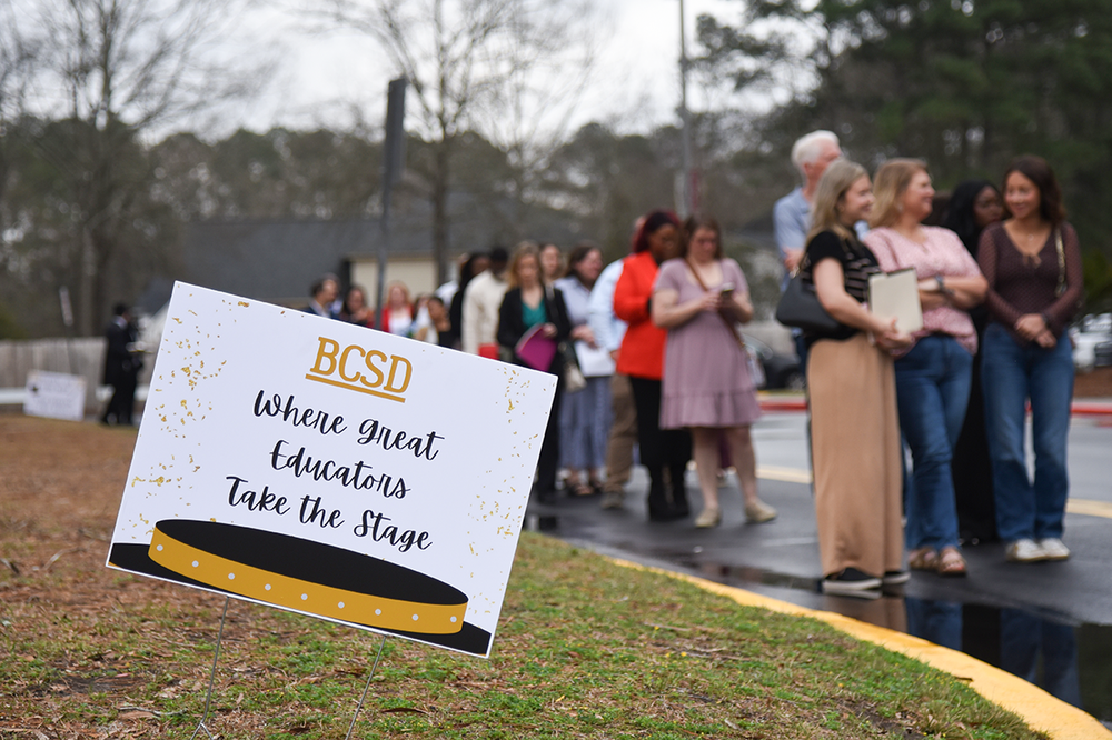 sign out front with line of people in the background
