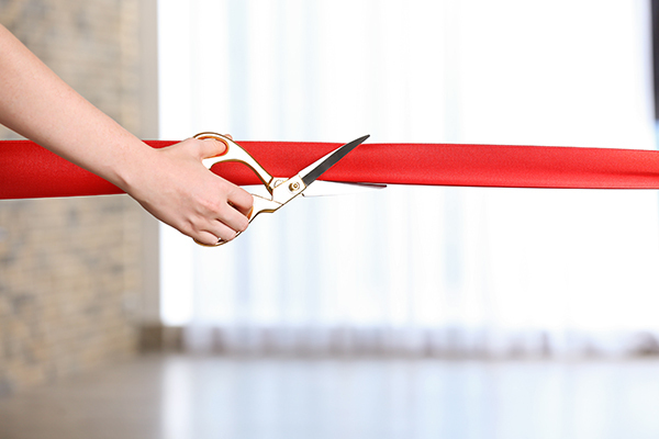 person cutting a red ribbon with scissors