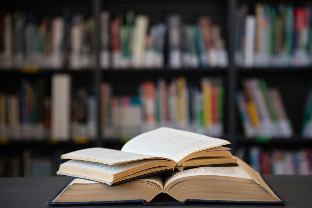 books open in front of library shelves