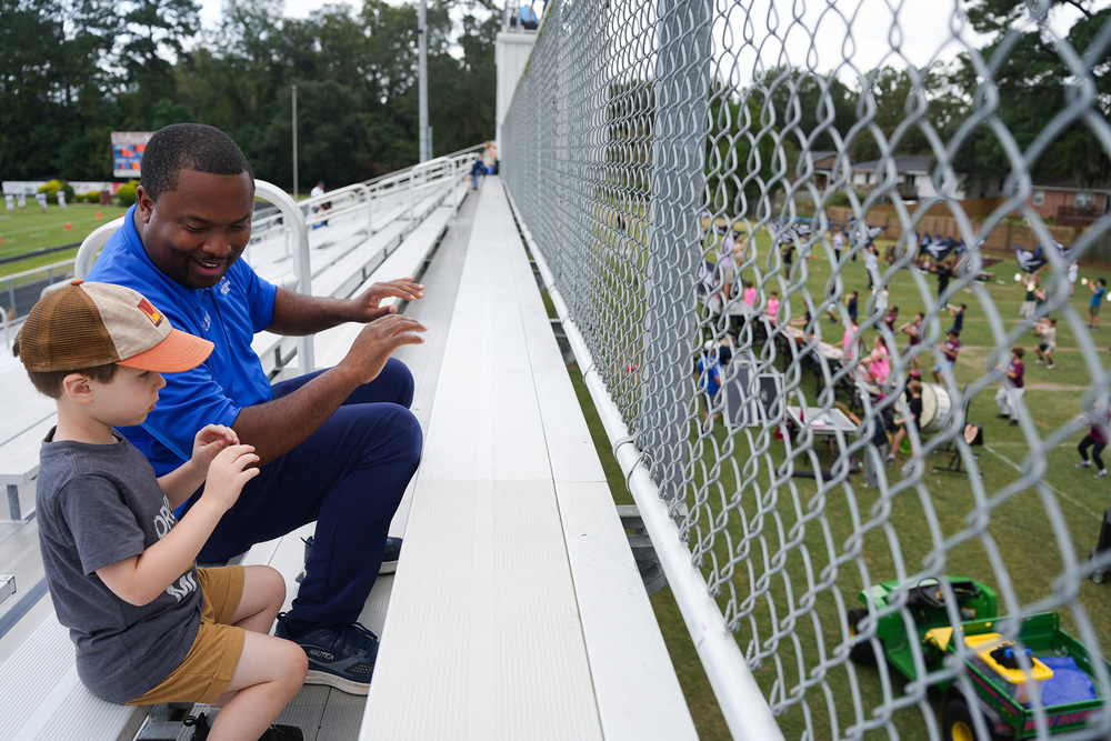 finley and andre conducting in stands while watching marching band students