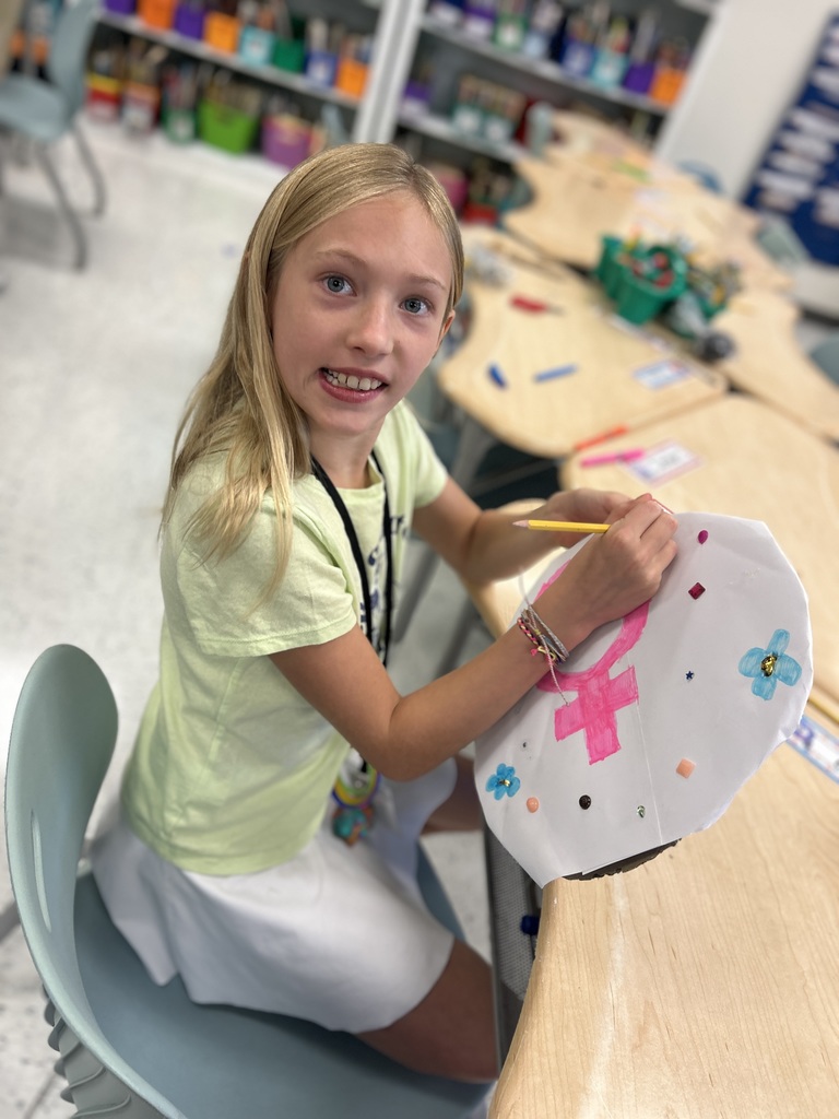 The student finishes creating her shield for her cabin.