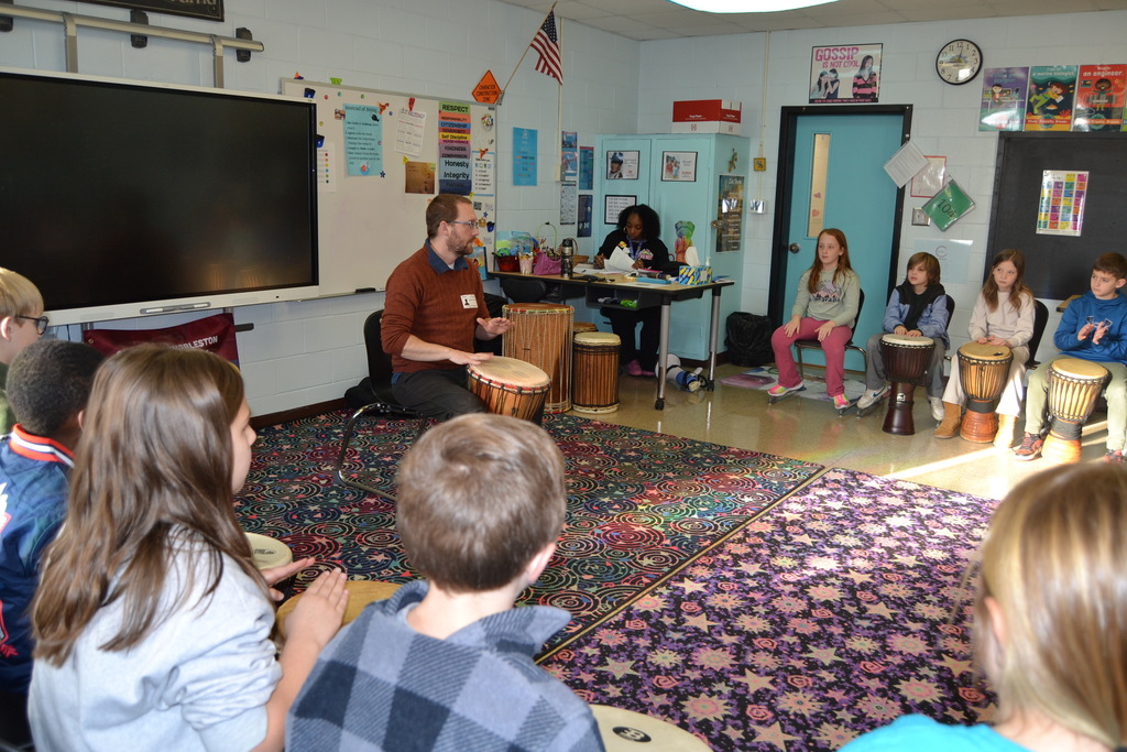 Students learning to play the drum with an artist in residence