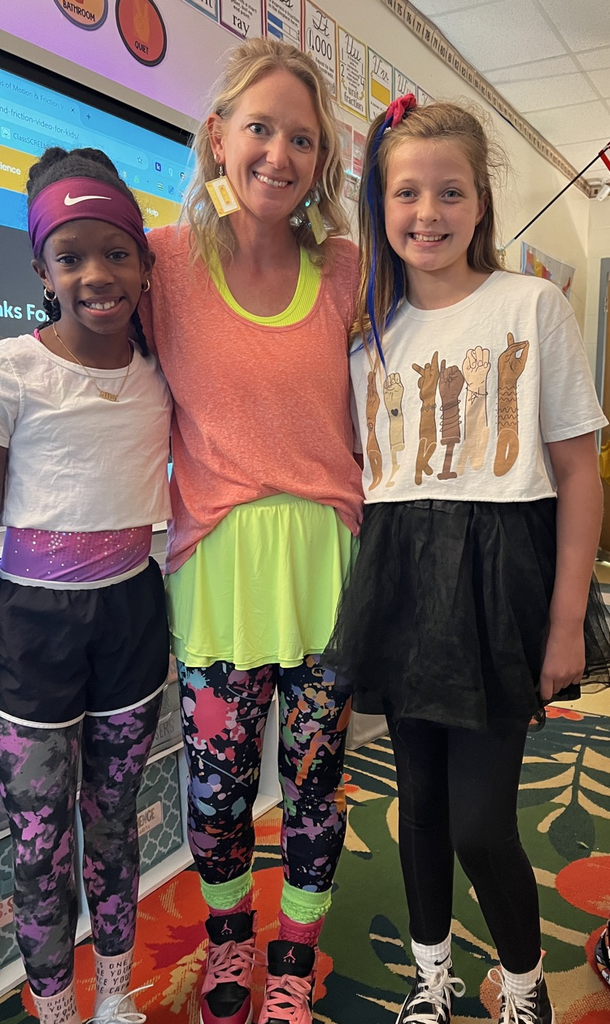 teacher smiling with students in bright clothing 