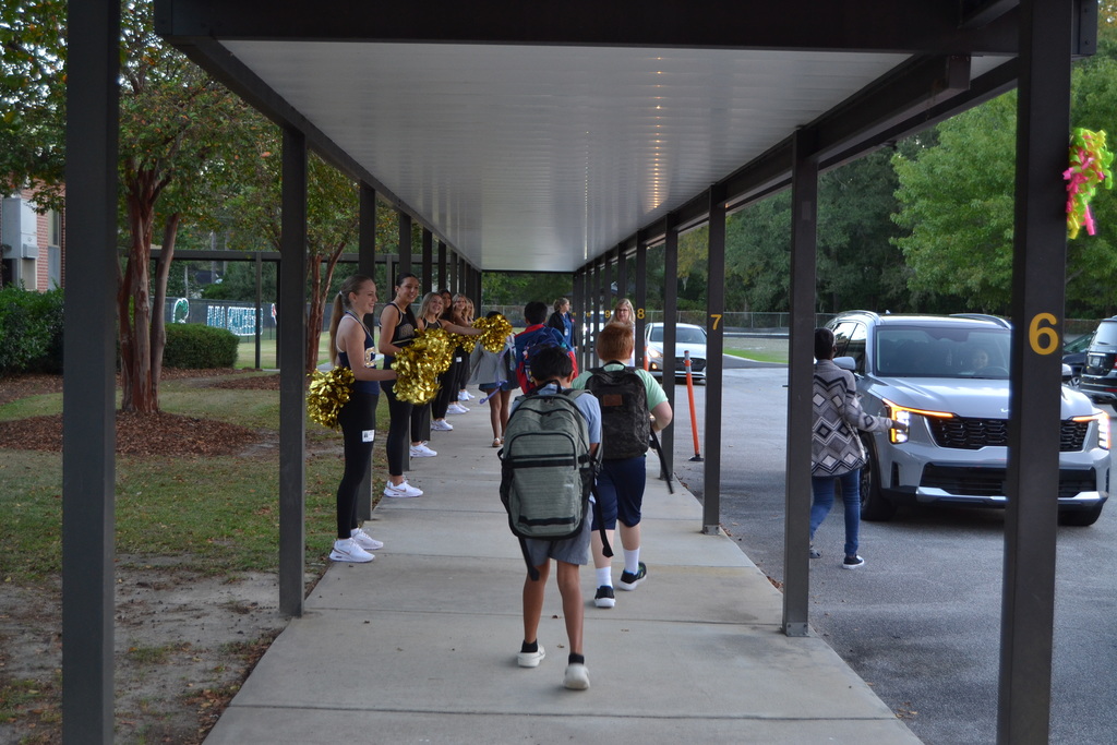 Kids walking and cheerleaders standing with pom poms