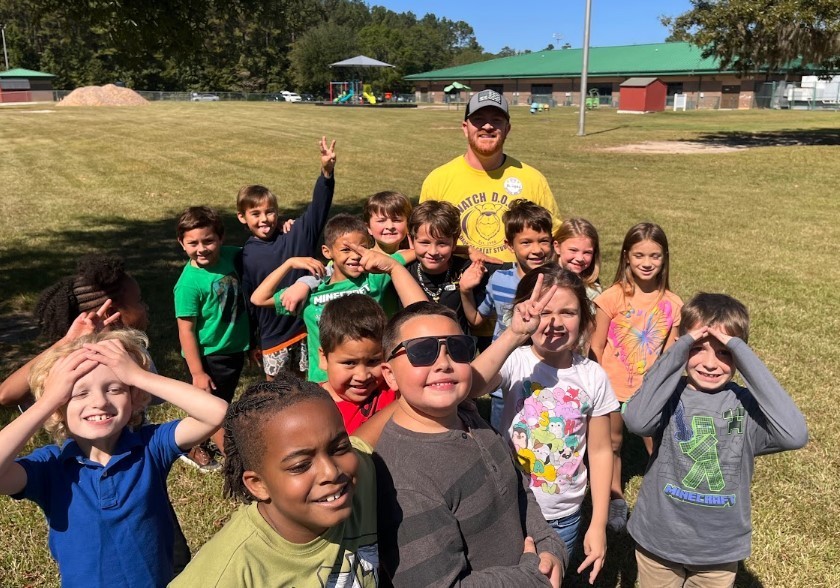 Watch dog volunteer pictured outside in a large group with our second graders posing for a picture