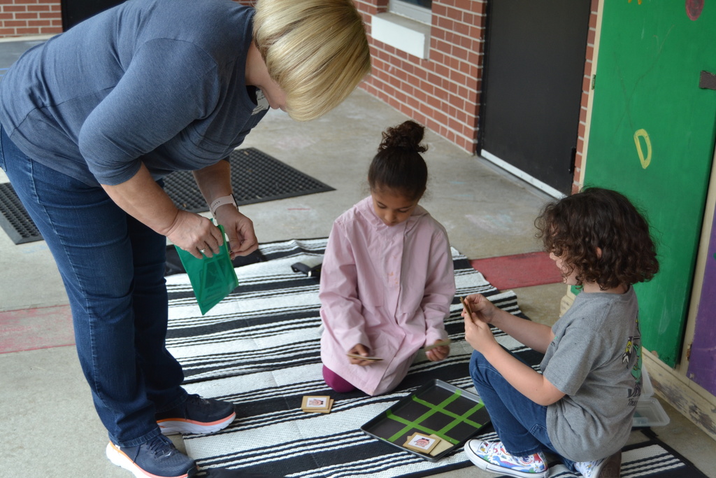Woman showing a little boy and girl how to play tic tac toe