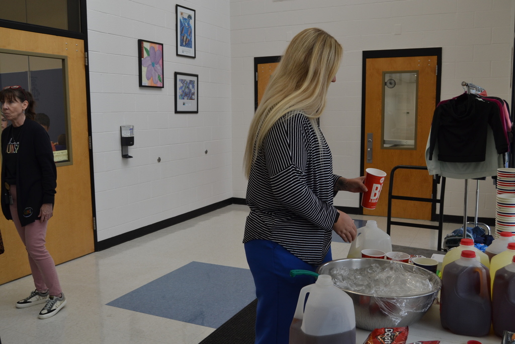 A lady with a cup in her hand next to a bowl of ice. 