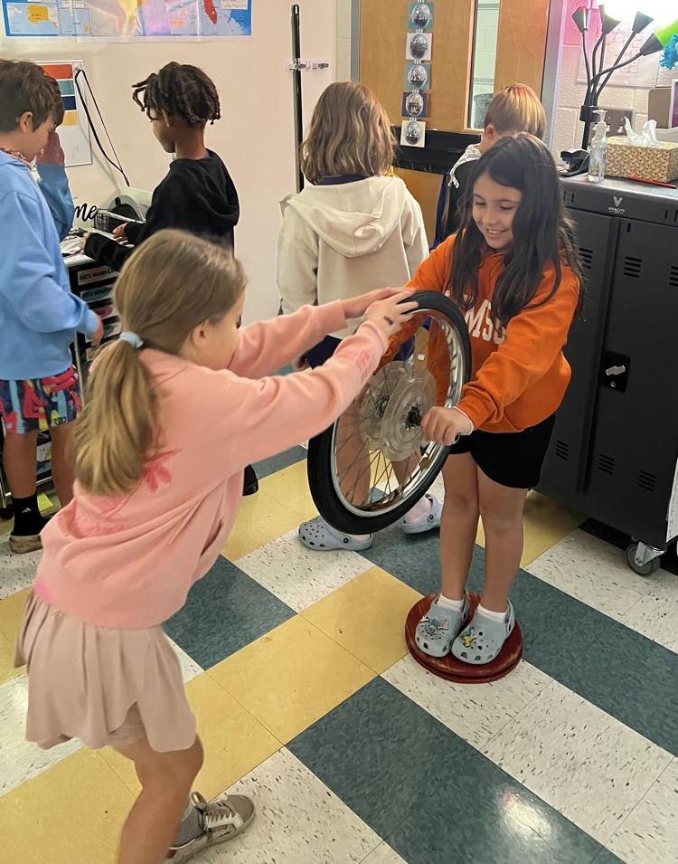 student with bike tire standing on spinning platform