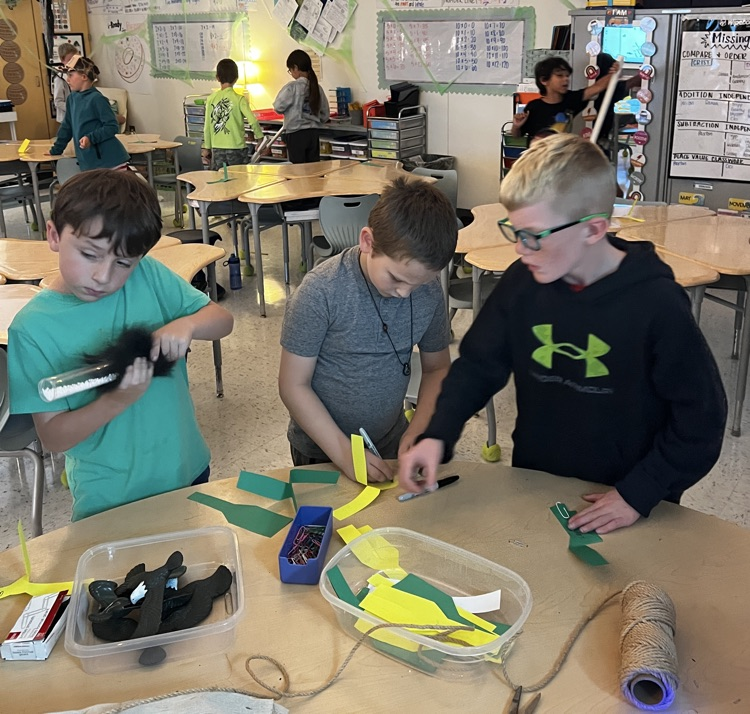 students around teacher desk making paper helicopters