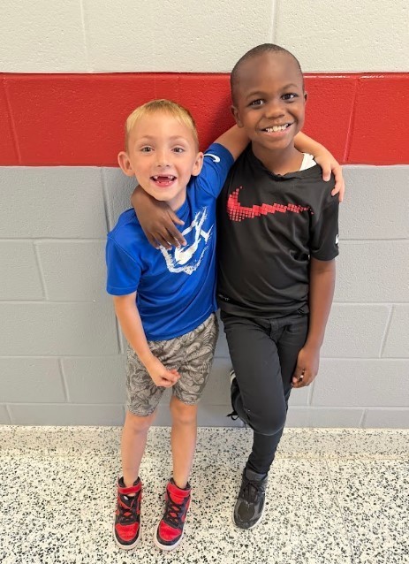 Two young boys wearing matching nike shirts with arms around one another and big smiles