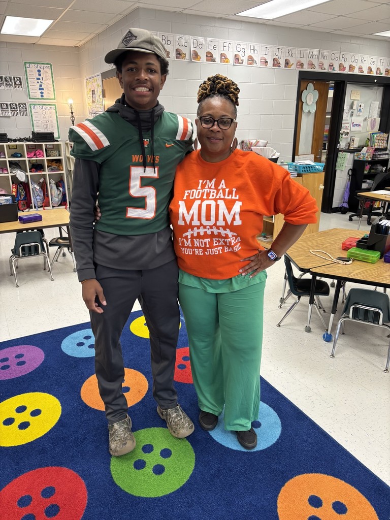 Teacher and football player pose the morning of our homecoming parade to celebrate the local high school football game.