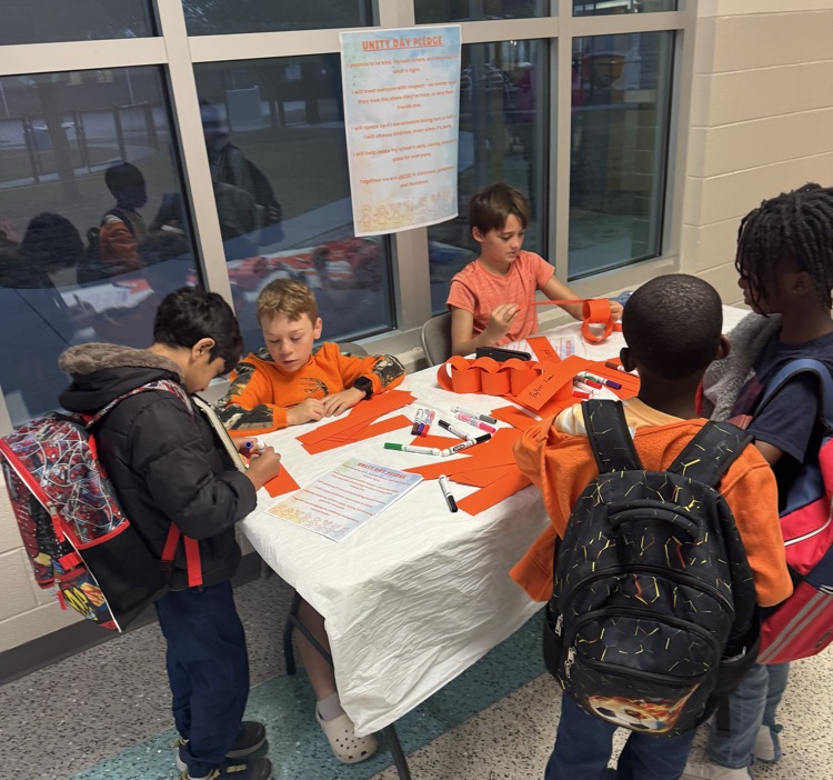 students at table signing orange link