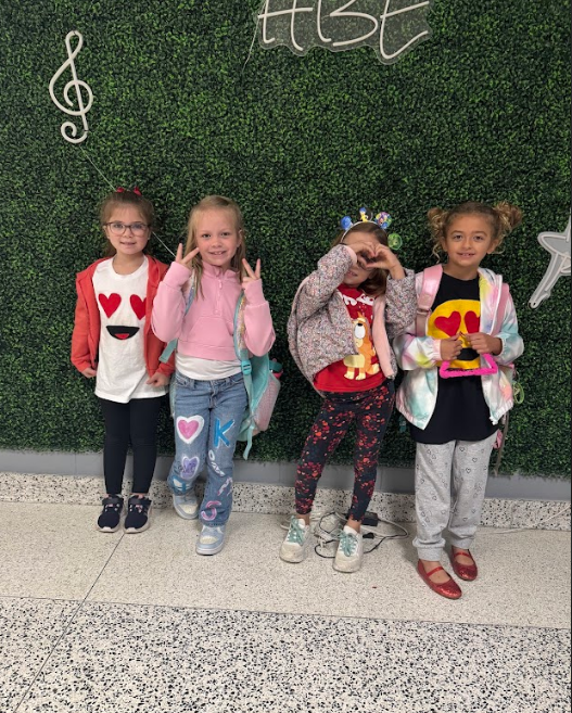 Group photo of four girls with fun peace sign and heart hand signals with emoji shirts.