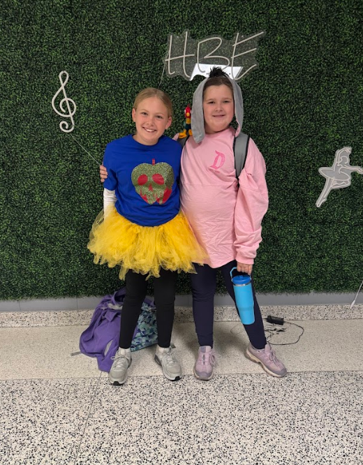Two girls, one with donkey headband ears from Winnie the Pooh, pose for disney day.