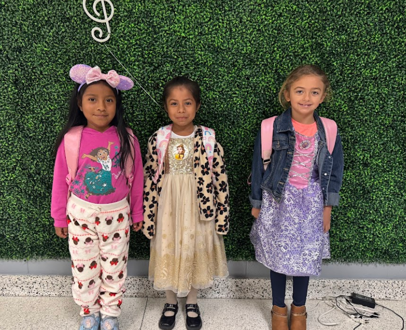 Three young girls dressed for disney day, with mouse ears, and disney dresses. 