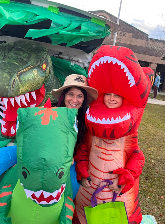 A teacher and student smile in the blow-up dinosaur costumes.